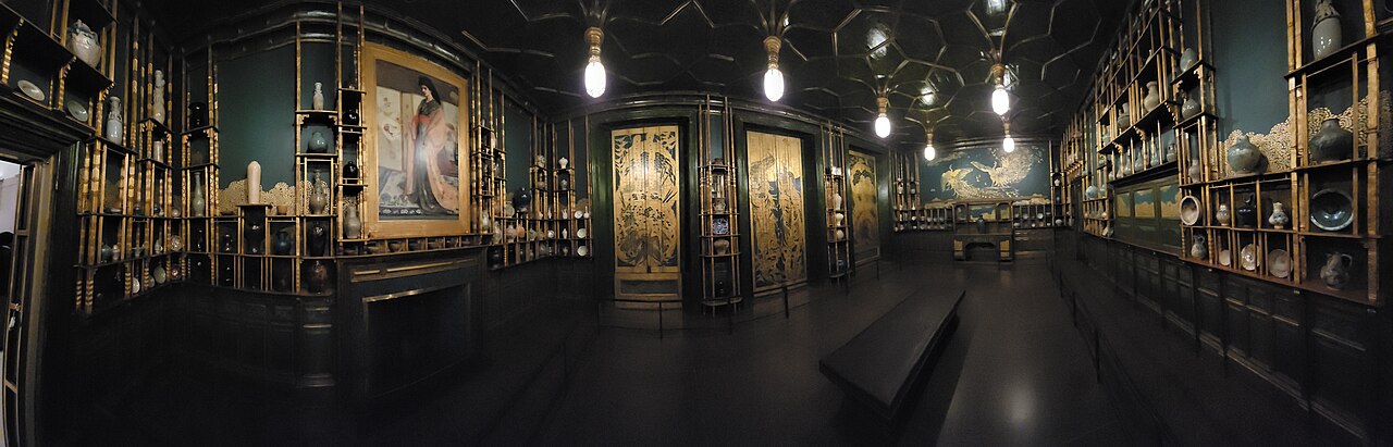 Freer美術館のPeacock Room。2023年の館内を入口側から見渡す。左の暖炉上に同じ《Princess》があり、床中央に食卓はない。パノラマは横方向の寸法を歪める。